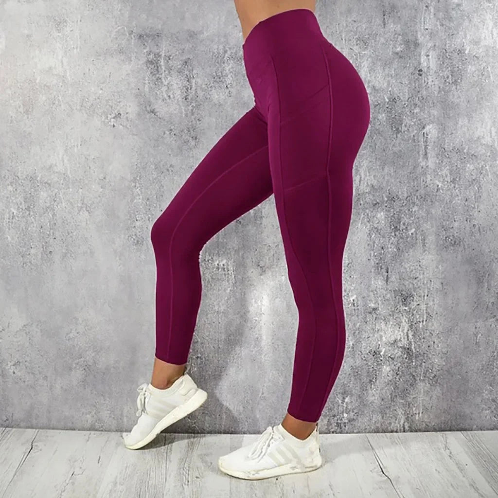 Person wearing maroon leggings and white sneakers against a gray concrete wall.