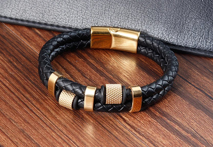 Black braided leather bracelet with gold accents on a wooden surface