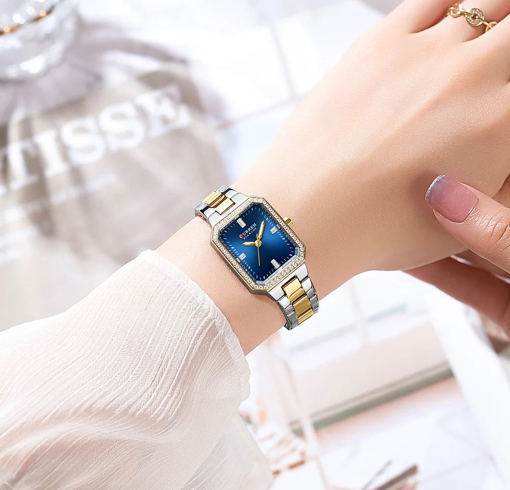 Wristwatch with blue face and gold accents on a wrist, blurred background