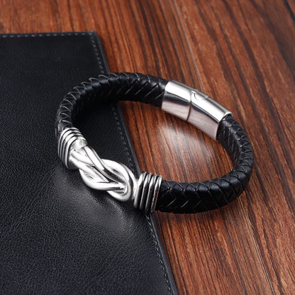 Black braided leather bracelet with silver clasp on a wooden surface