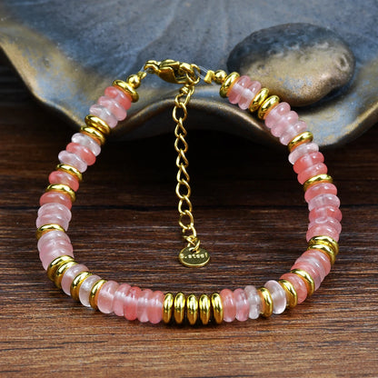 Bracelet with pink and gold beads on a wooden surface