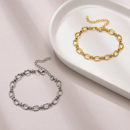 Gold and silver chain bracelets on a white dish with a light pink background