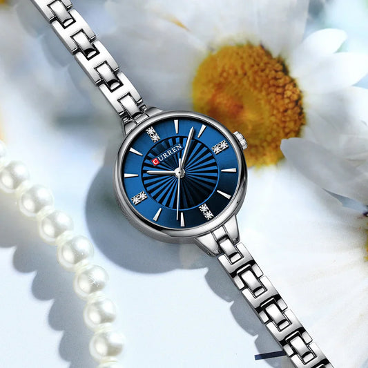 Silver watch with blue face on a white flower background