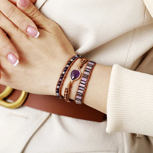 Close-up of a wrist wearing multiple bracelets with a neutral background