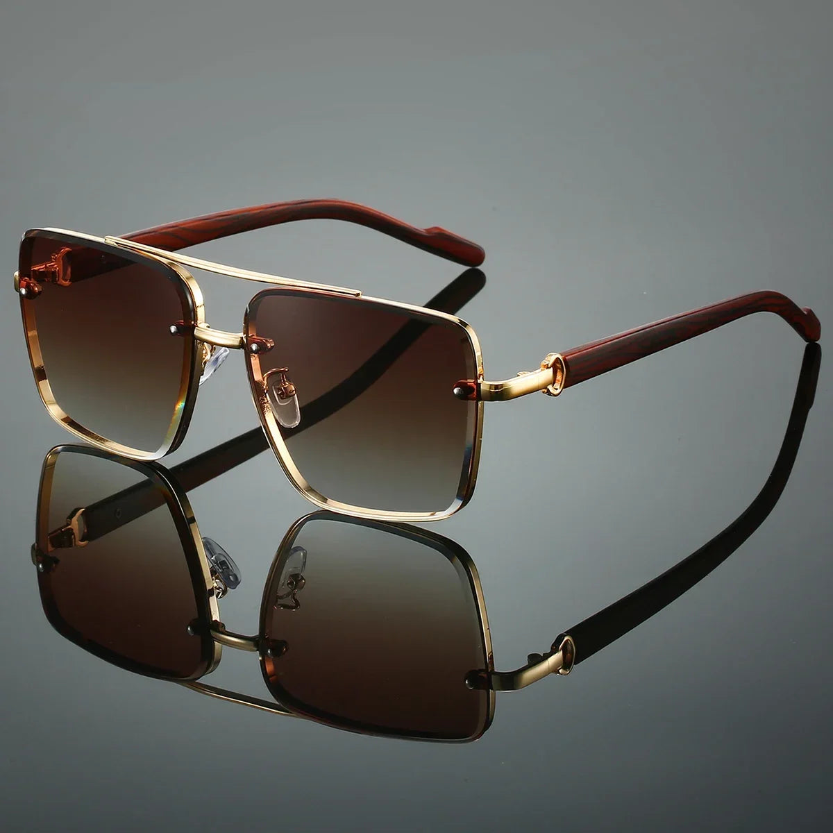 Sunglasses with gold frame and brown lenses on a reflective surface