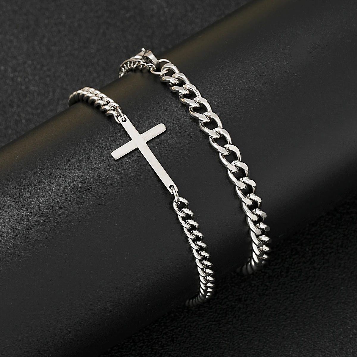 Silver chain bracelet with a cross pendant on a dark surface