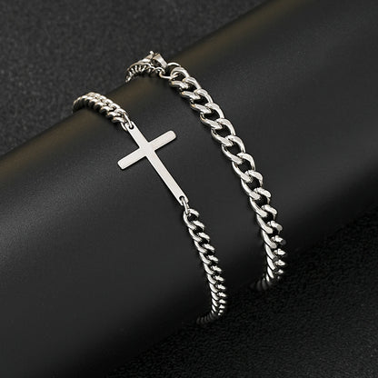 Silver chain bracelet with a cross pendant on a dark surface