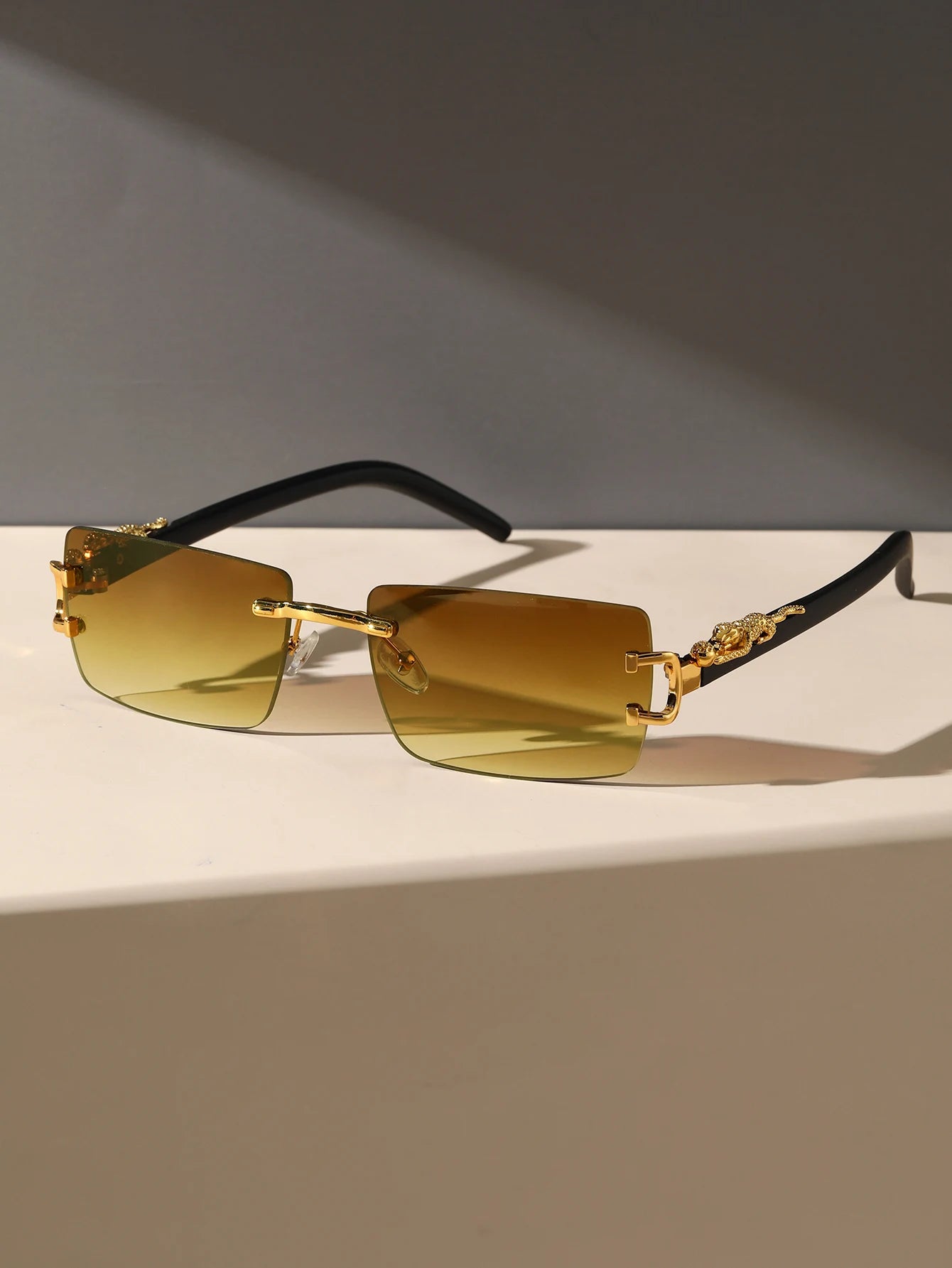 Gold-rimmed sunglasses with brown lenses on a reflective surface