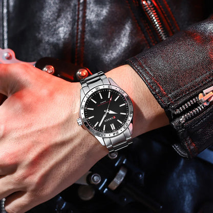 Close-up of a wrist wearing a silver watch with a black face, against a dark background.