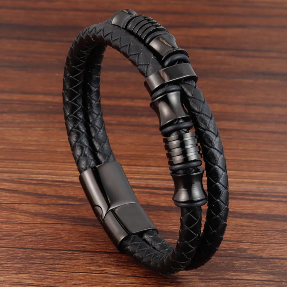 Black braided leather bracelet with metal clasp on a wooden surface