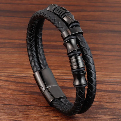 Black braided leather bracelet with metal clasp on a wooden surface