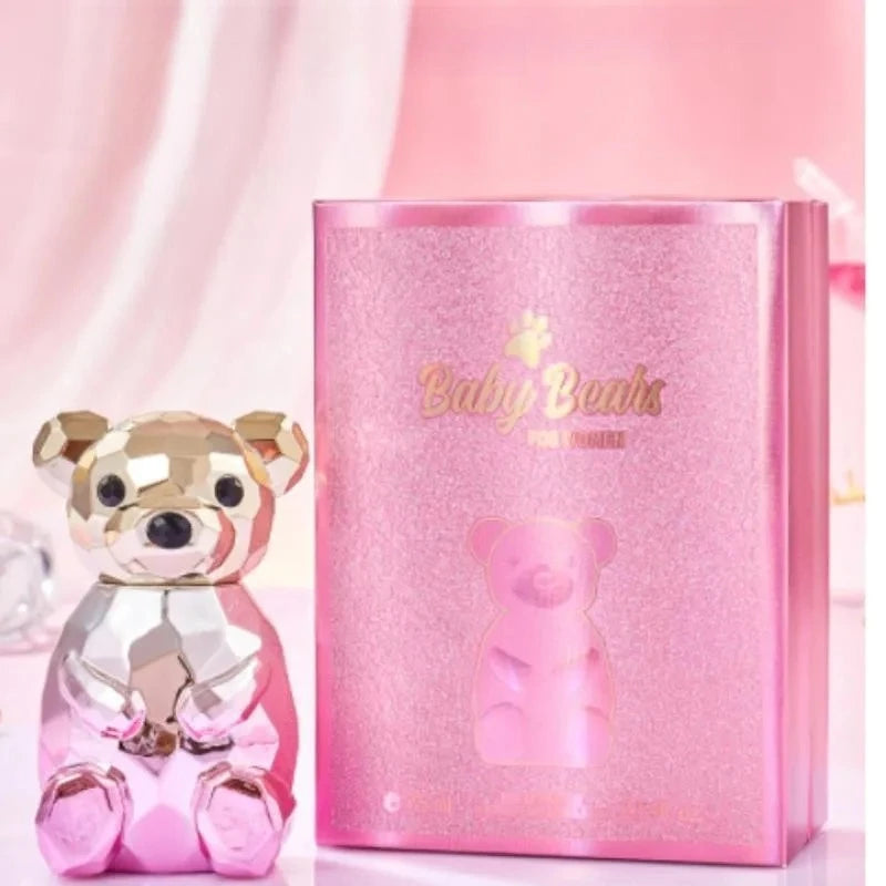 Pink teddy bear figurine next to its packaging on a pink background