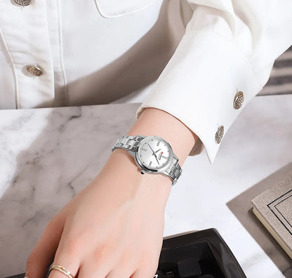 Silver watch on a wrist with a white jacket and marble surface in the background