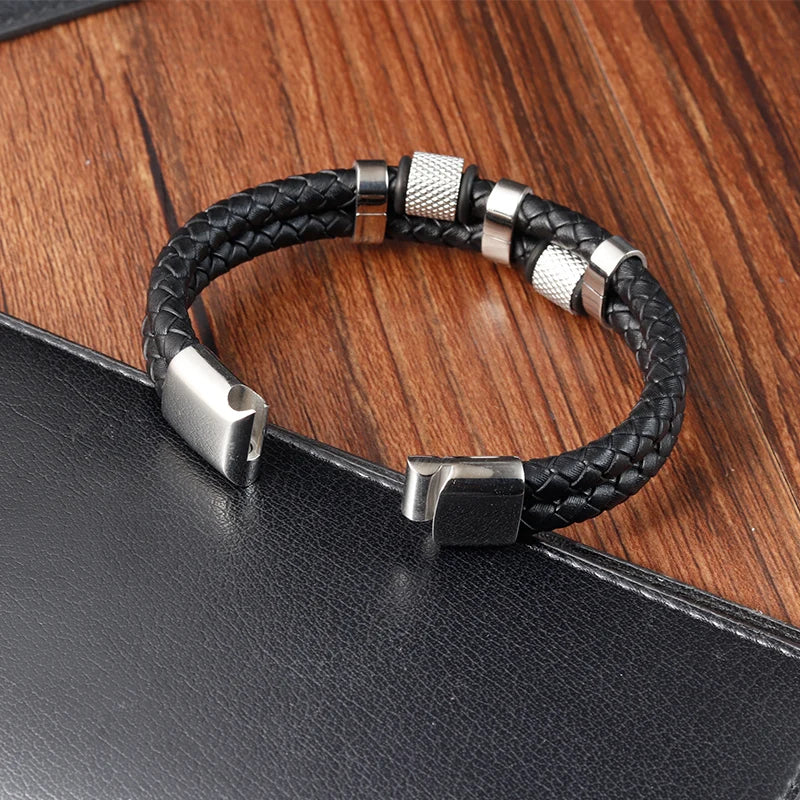 Black braided leather bracelet with silver metal clasps on a wooden surface