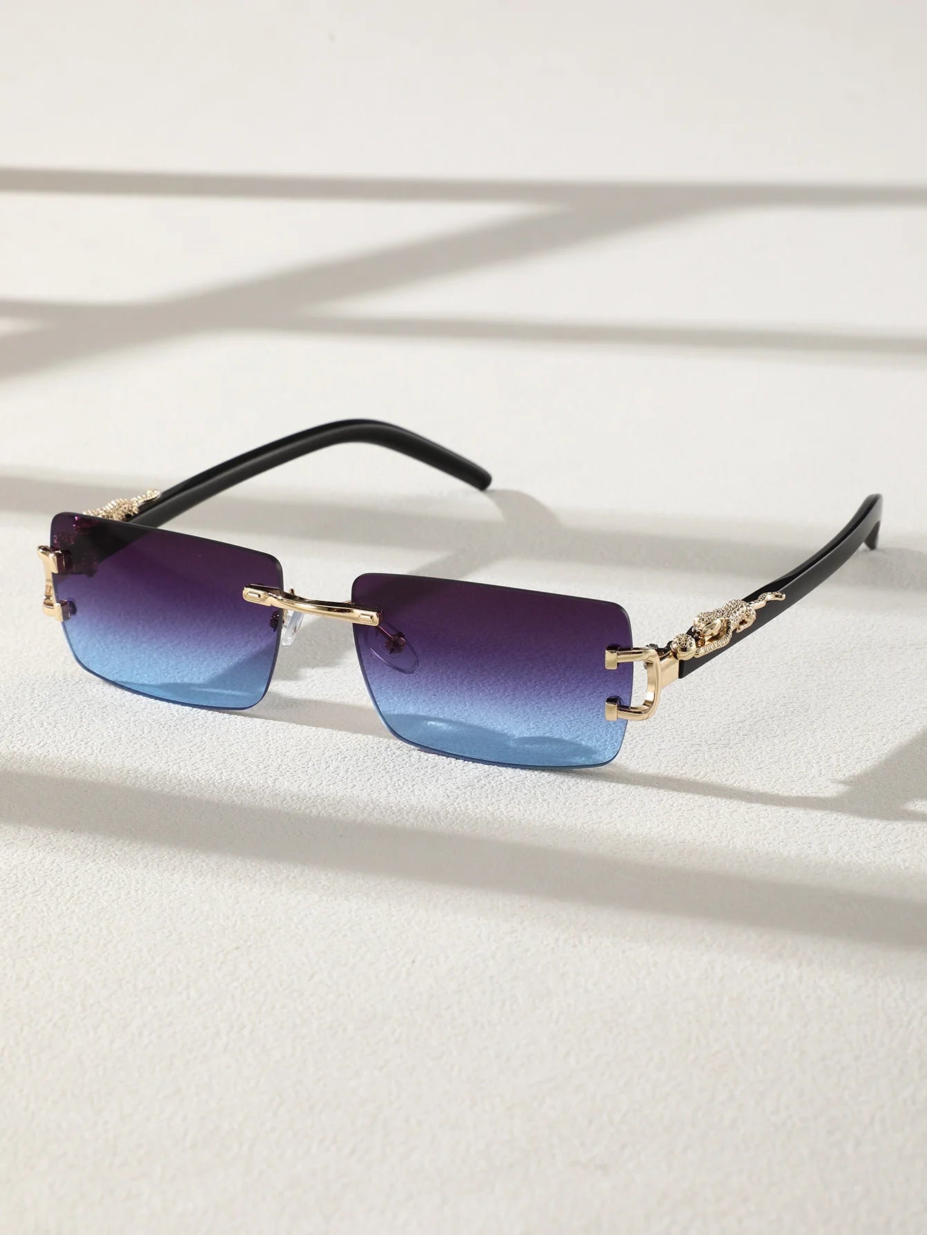 Sunglasses with blue gradient lenses and gold frames on a light background
