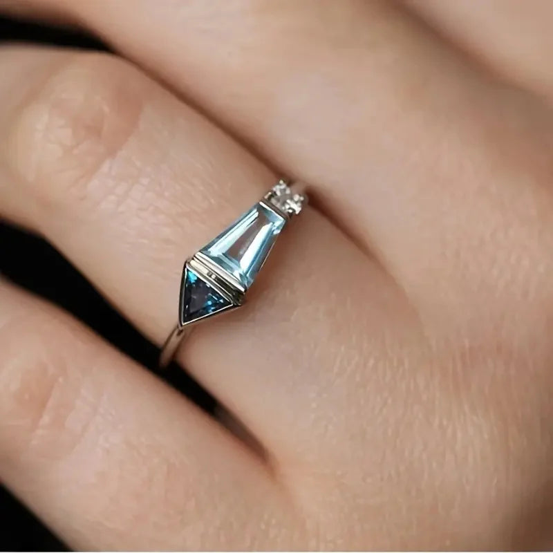 Silver ring with a blue gemstone on a finger