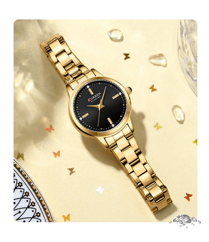 Gold wristwatch with black dial on a decorative background