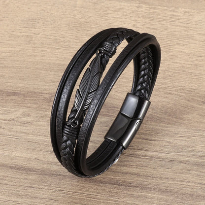 Black braided leather bracelet with feather design on a wooden surface