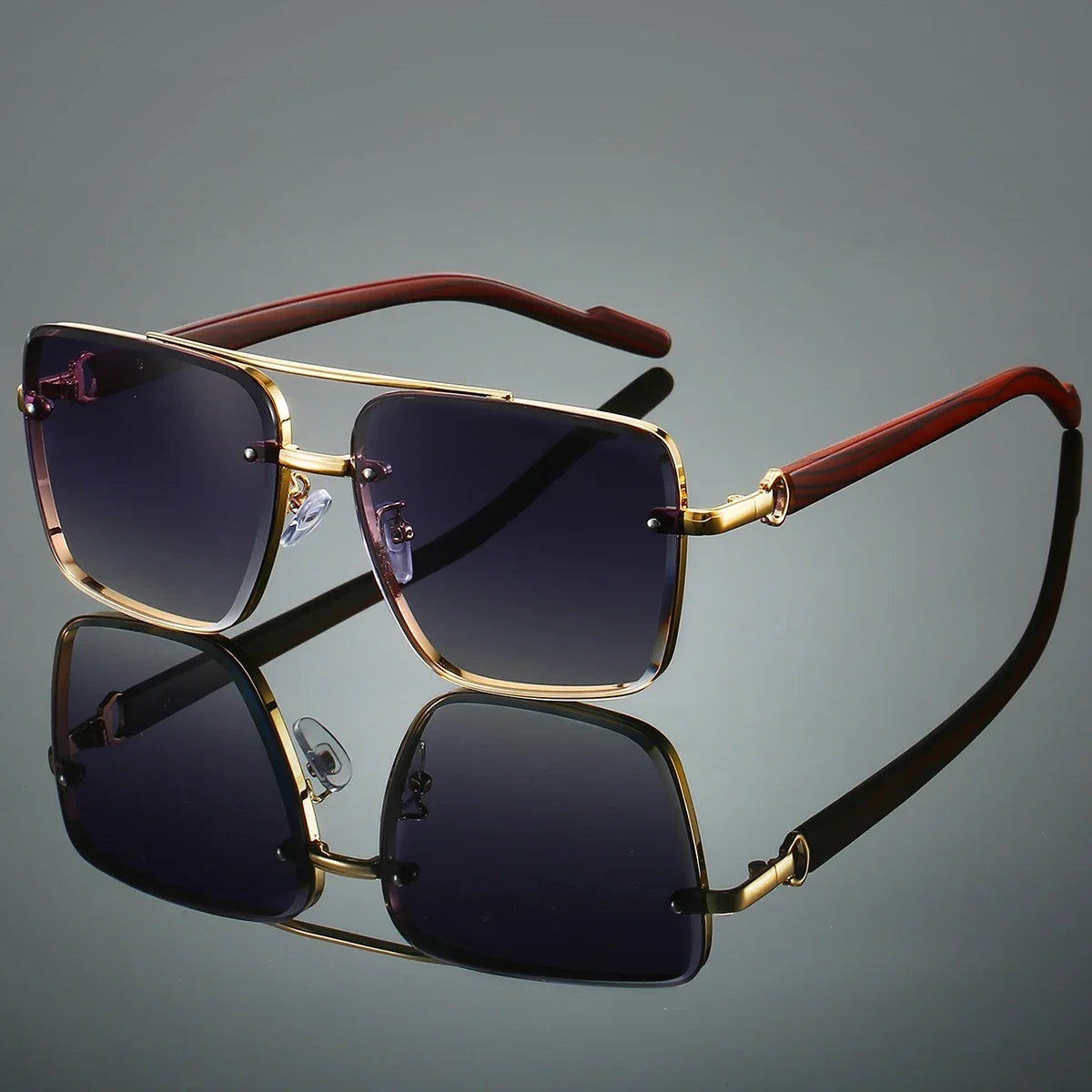 Sunglasses with gold frame and dark lenses on a reflective surface with a gray background