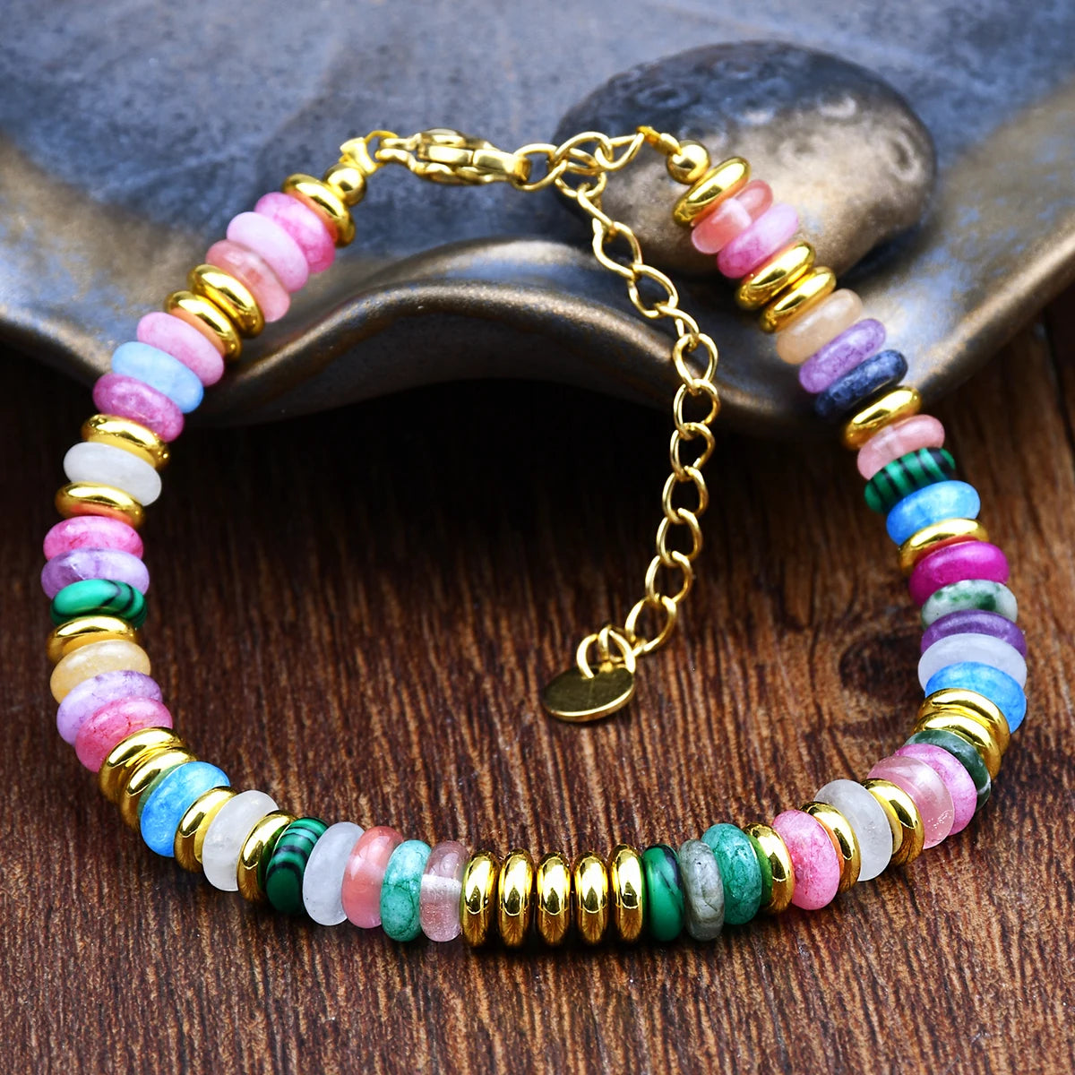 Multicolored beaded bracelet with gold accents on a wooden surface