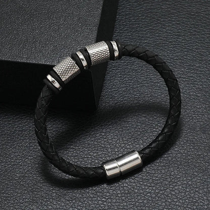 Black braided leather bracelet with silver metal clasps on a dark textured surface