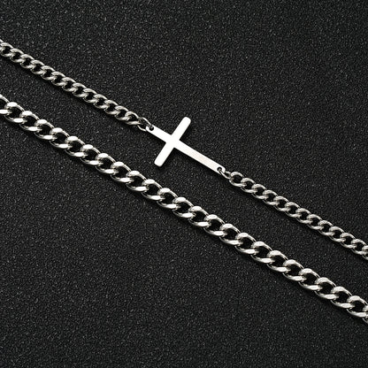 Two necklaces on a black background, one with a silver cross pendant and the other with a thick chain.