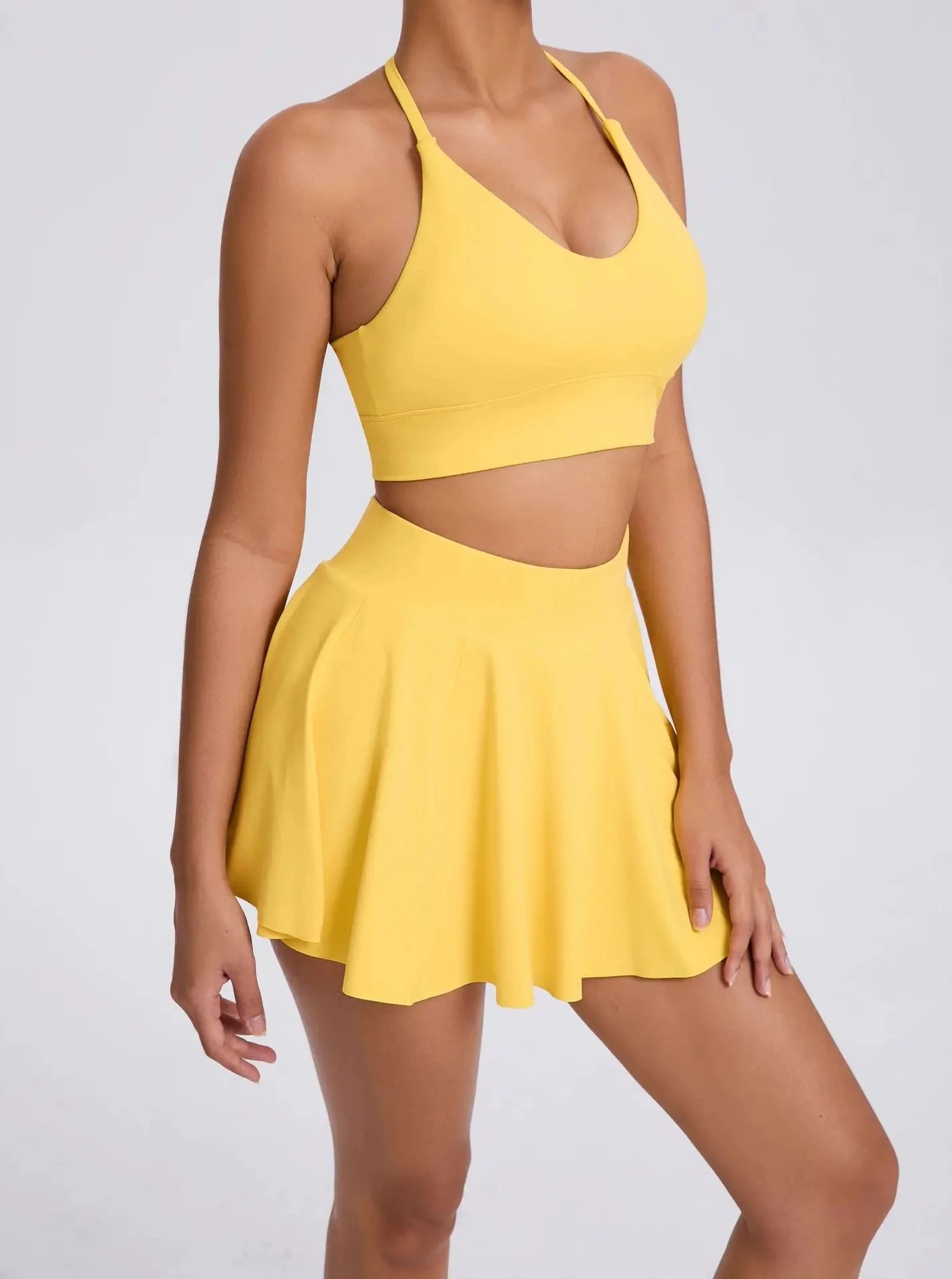 Yellow two-piece outfit with a halter top and skirt on a plain background