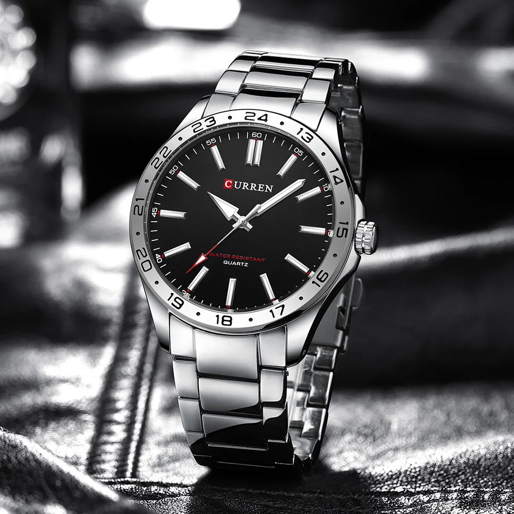 Curren watch with black dial and silver metal strap on a blurred background