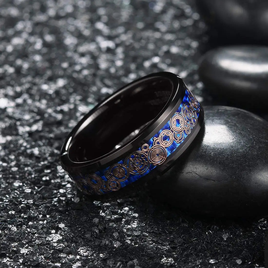 Black ring with blue and gold design on a dark textured surface