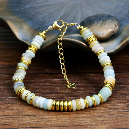 Bracelet with gold and white beads on a wooden surface