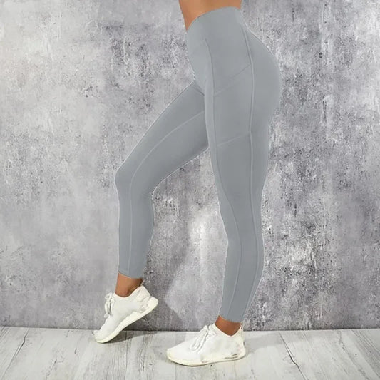 Person wearing gray leggings and white sneakers against a concrete wall.