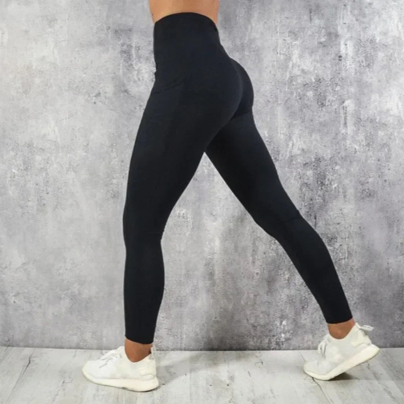 Person wearing black leggings against a gray concrete wall.