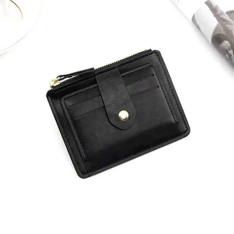 Black wallet with a gold button on a white surface