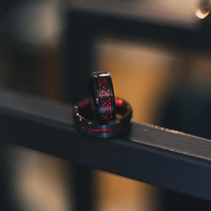 Close-up of a black ring with red detailing on a metallic surface.