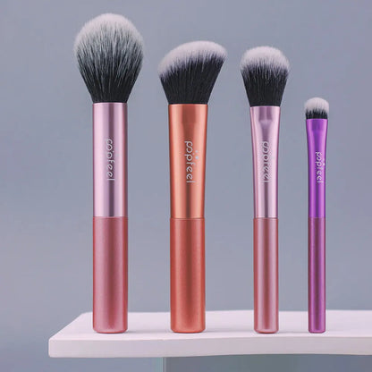 Four makeup brushes with pink and purple handles on a gray background