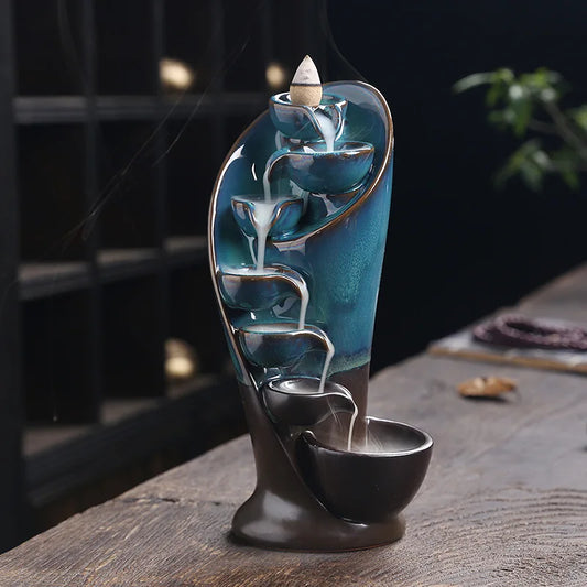 Decorative water fountain with blue liquid and white candle on a wooden surface