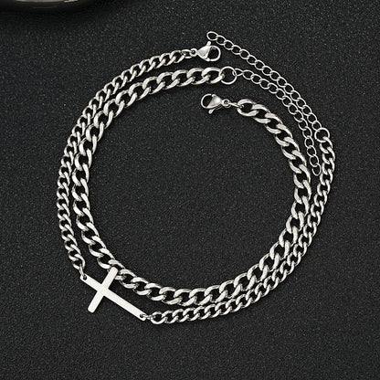 Silver chain bracelet with a cross charm on a black background