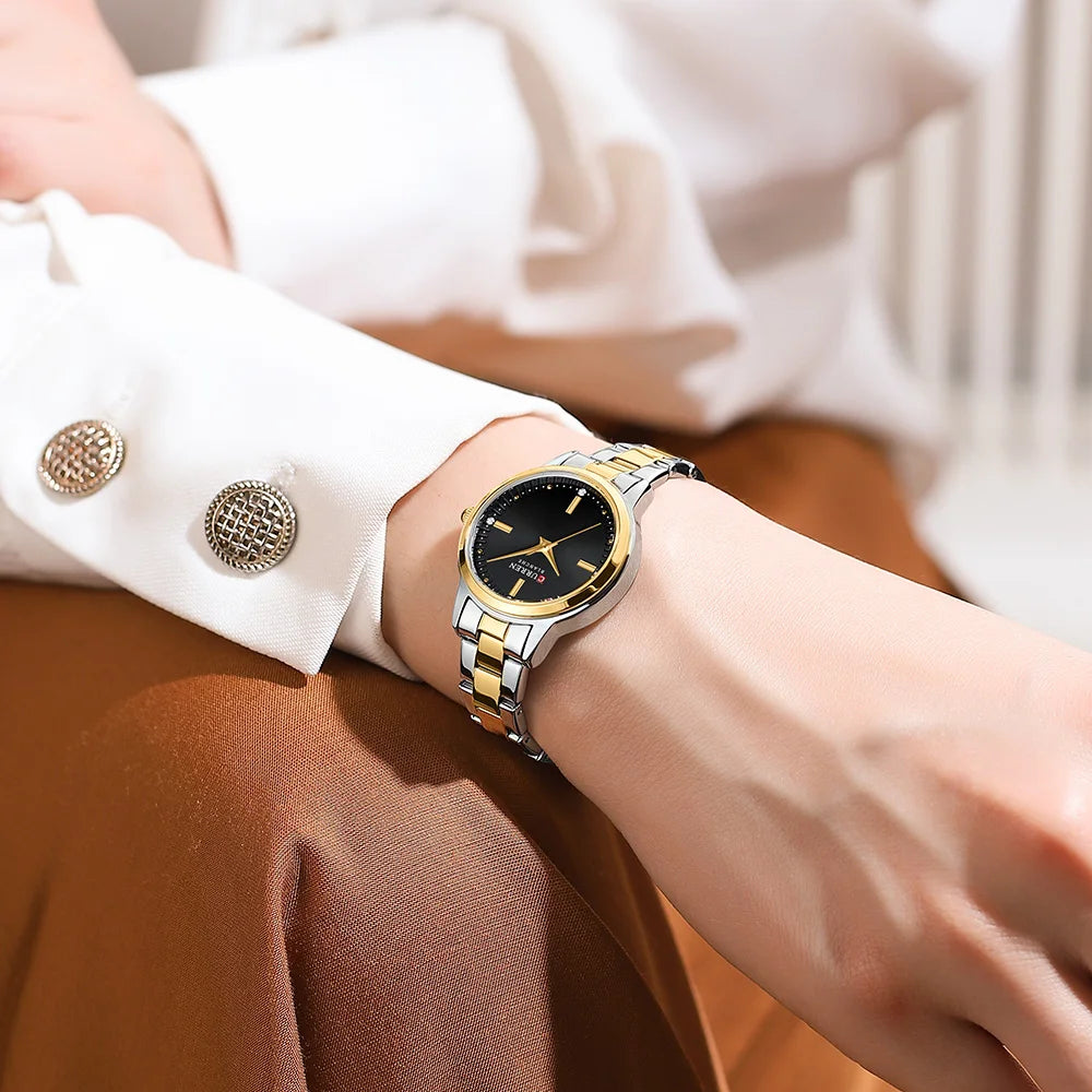 Gold and silver watch on a person's wrist with a blurred background