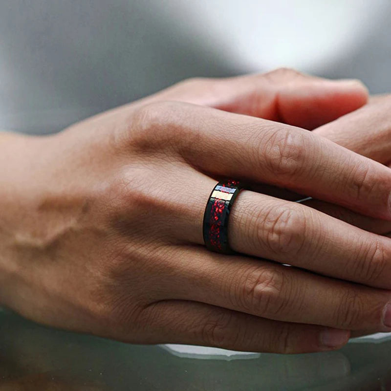 Hand wearing a ring with red and black design on a blurred background
