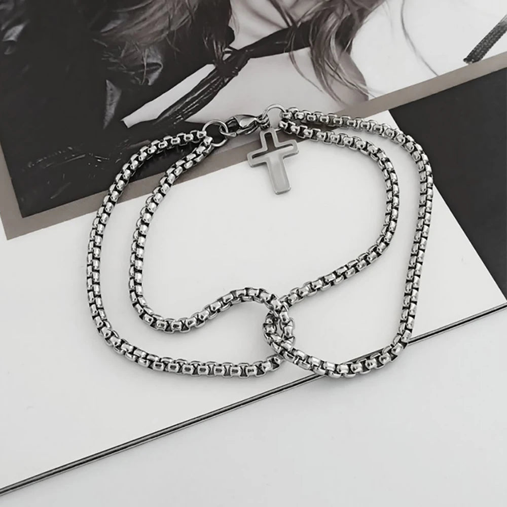 Silver chain necklace with a cross pendant on a white surface