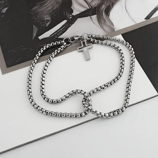 Silver chain necklace with a cross pendant on a white surface