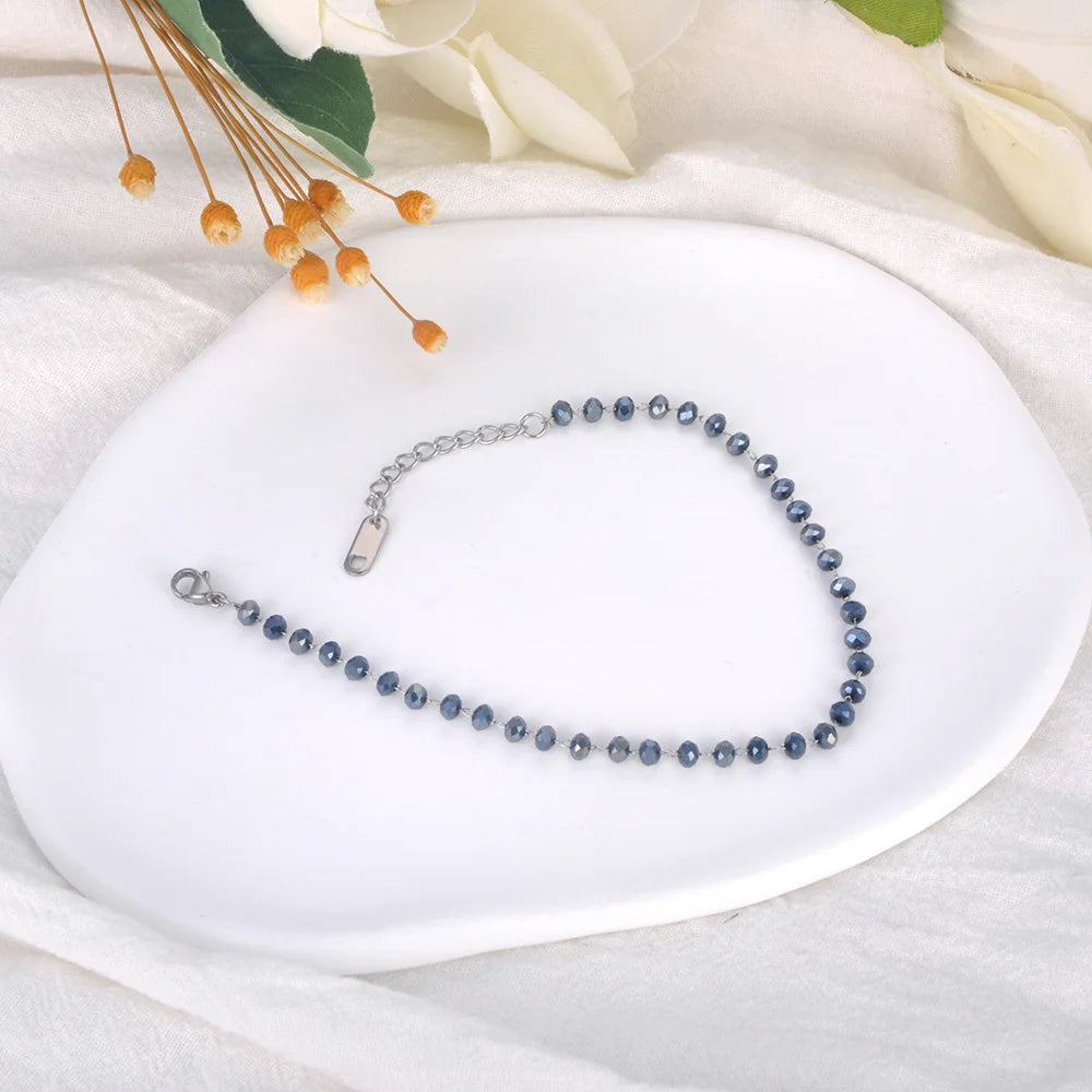 Blue beaded necklace on a white dish with flowers in the background