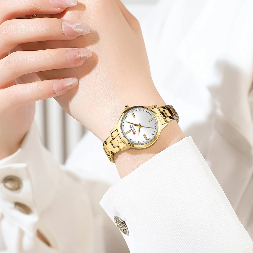 Gold wristwatch on a person's wrist with a blurred background