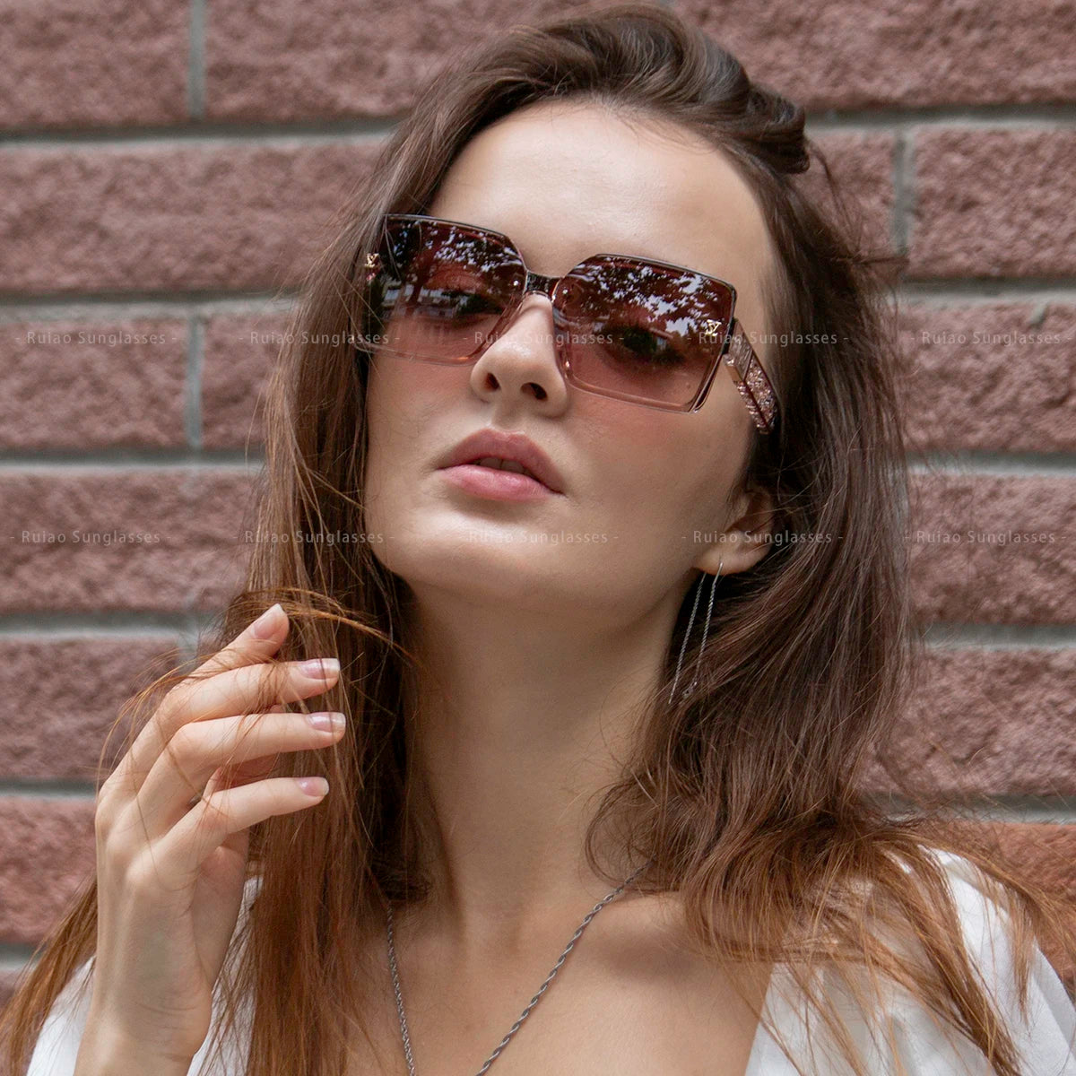 Woman wearing sunglasses with a brick wall background