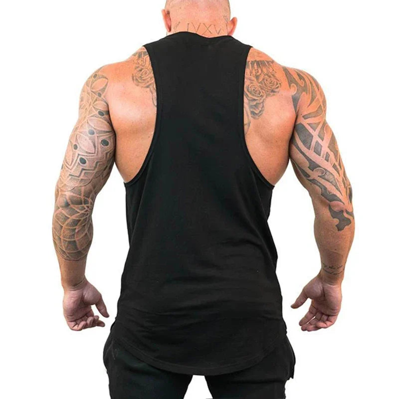 Man wearing a black tank top with visible tattoos on arms and back against a white background