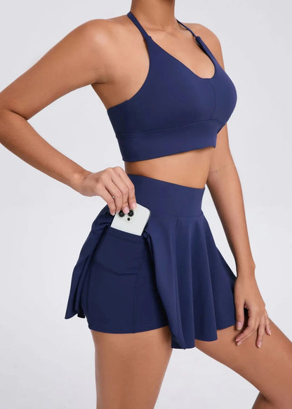 Person wearing a navy blue sports bra and skirt set on a white background